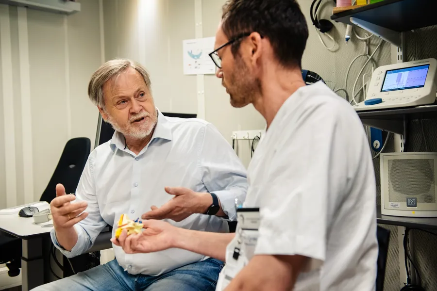 En lege som viser en pasient noe på nettbrettet