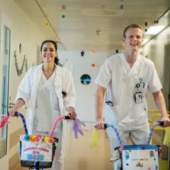 En mann og kvinne på sparkesykler i en sykehusgang